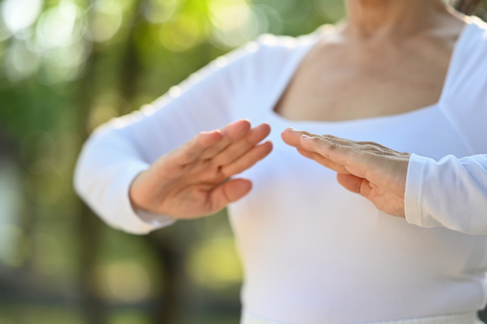 Cropped shot senior woman practicing Chi Kung or Tai Chi in nature. Healthy lifestyle concept.